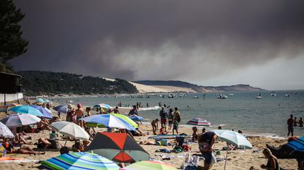 Strandgäste im südfranzösischen Pyla-sur-mer, mit Blick auf Waldbrände.