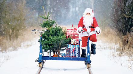 Mit einer Fahrraddraisine der Erlebnisbahn, beladen mit Geschenken, Ski und einem Weihnachtsbaum, ist ein Weihnachtsmann in Mellensee (Brandenburg) unterwegs.