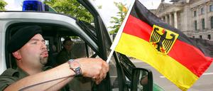Polizeiobermeister Marco Däfler befestigte bei der Fußball-Weltmeisterschaft 2006 vor dem Berliner Reichstag eine Deutschlandfahne an seinem Polizeiwagen.