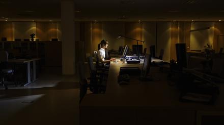 Eine Frau arbeitet allein in einem dunklen Büro (Symbolbild). 