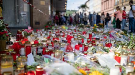Grablichter, Kerzen und Blumen liegen vor einem Kaufhaus in der Innenstadt von Würzburg.