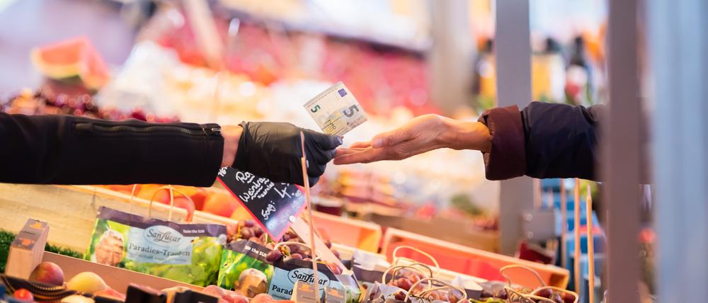 Geld wird auf einem Wochenmarkt im Berliner Ortsteil Schöneberg über eine Obst- und Gemüsetheke gereicht. Die Inflation in Berlin und Brandenburg steigt über acht Prozent laut dem Amt für Statistik Berlin-Brandenburg. +++ dpa-Bildfunk +++