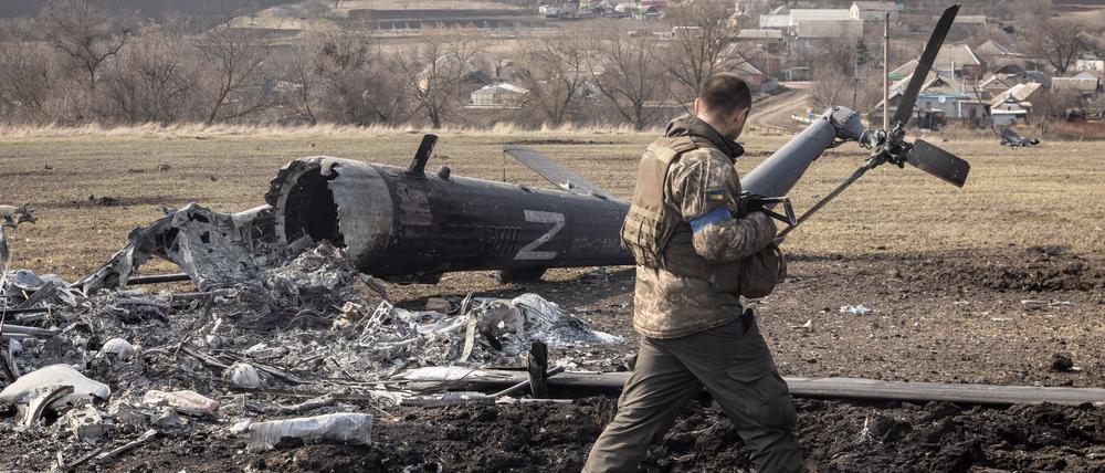 Ein ukrainischer Soldat betrachtet einen abgeschossenen russischen Militärhelikopter in Mala Rohan nahe Charkiw.