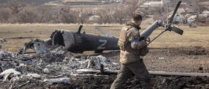 Ein ukrainischer Soldat betrachtet einen abgeschossenen russischen Militärhelikopter in Mala Rohan nahe Charkiw.