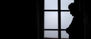 Ein Mann steht am Fenster seiner Wohnung. (Symbolbild, gestellte Szene)