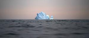 Grönland, Kulusuk: Ein Eisberg schwimmt bei Sonnenuntergang auf dem Meer.