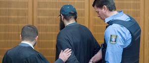Ein Justizbeamter nimmt dem mutmaßlichen Islamisten Halil D. (M) am 21.01.2016 im Verhandlungssaal des Landgerichts in Frankfurt am Main (Hessen) die Handschellen ab, während sein Verteidiger Ali Aydin (l) ihm die Hand auf den Arm legt. 