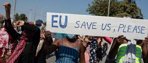 Migrantinnen und Migranten auf Lesbos rufen bei einem Protest Parolen und halten ein Schild mit der Aufschrift: EU, rette uns bitte. 