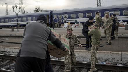 Helfer und Militäs beladen einen Zug mit Hilfsgütern.
