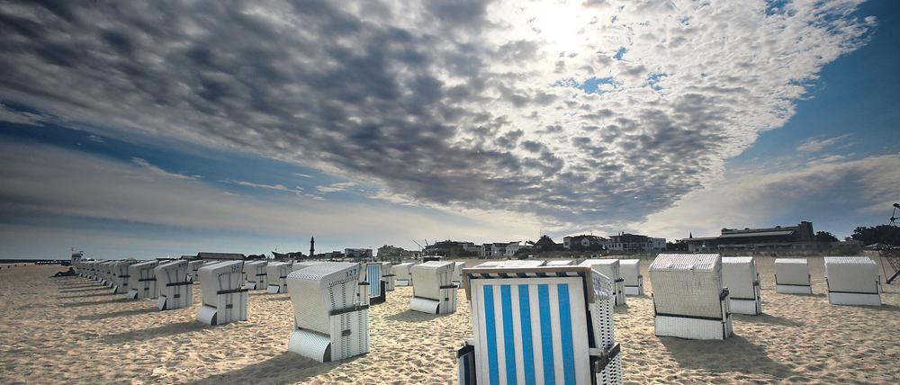 dpatopbilder Über den Strandkörben des Ostseebades Rostock-Warnemünde (Mecklenburg-Vorpommern) kämpft sich die Sonne am 25.08.2015 durch die Wolken. Das hochsommerliche Wetter ist vorerst vorbei. Foto: Bernd Wüstneck/dpa +++(c) dpa - Bildfunk+++