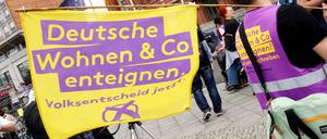 Ein Demonstrant hält eine Fahne mit der Aufschrift „Deutsche Wohnen und Co enteignen“ während einer Kundgebung vor dem Roten Rathaus nach der Vorstellung des Abschlussberichts der Expertenkommission „Vergesellschaftung großer Wohnungsunternehmen“.