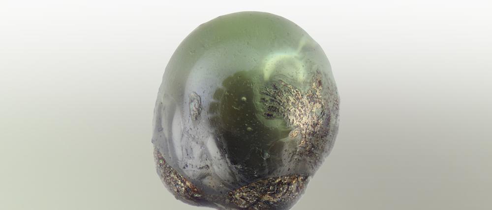 Kleiner grüner Stein. Dieser Mikrometeorit ist mit seinen 0,2 Millimetern Durchmesser kaum mit bloßem Auge zu erkennen - und deshalb hier in stereomikroskopischer Aufnahme zu sehen. Er stammt von einem Dach in Berlin. 