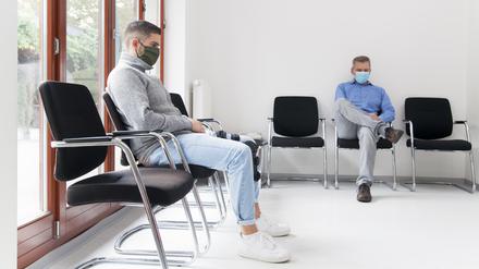 Patienten warten im Wartezimmer einer Arztpraxis. Deutschlands Kassenärzte wollen sich in der Coronakrise als eine Art Bollwerk vor die Krankenhäuser stellen. 