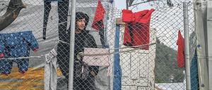 In einem Flüchtlingscamp auf Samos steht ein Mann hinter einem Zaun, an dem Wäschestücke zum Trocknen aufgehängt sind.