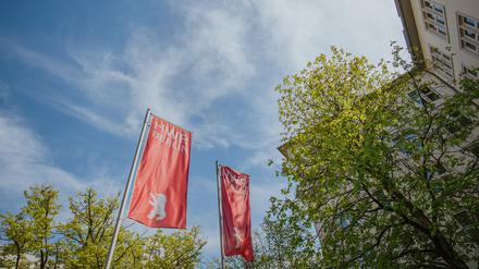 Ein Blick in den Himmel, mit einer Ecke des Hauptgebäudes der HWR Berlin und den Flaggen der Hochschule.