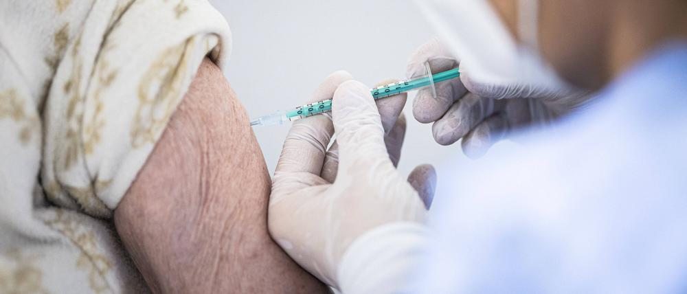 Eine ältere Person bekommt eine Impfung gegen Corona im Impfzentrum in Schönefeld.