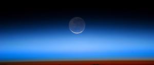 Der Mond, aufgenommen von der Internationalen Raumstation. Die helle Sichel wird von der Sonne beschienen, der blasser erscheinende Teil von der Erde.